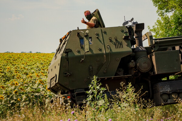 Член українського екіпажу HIMARS, прикріпленого до 148-ї бригади, показує великий палець, коли машина займає позицію на лінії фронту на сході України, щоб обстріляти ракети по російських позиціях, субота, 8 серпня 2026 р. (AP Photo/Dan Bashakov)